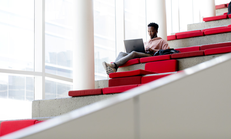 un étudiant assis dans les cages d'escalier du campus ETS