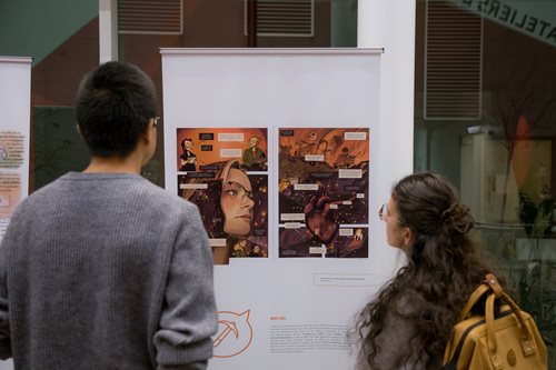 Participants of the vernissage from behind looking at a drawing board