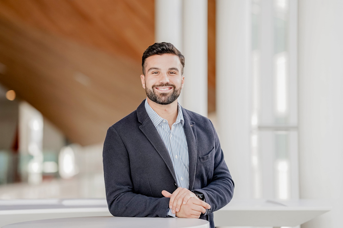 Un jeune professionnel souriant, élégant dans un espace moderne et lumineux.