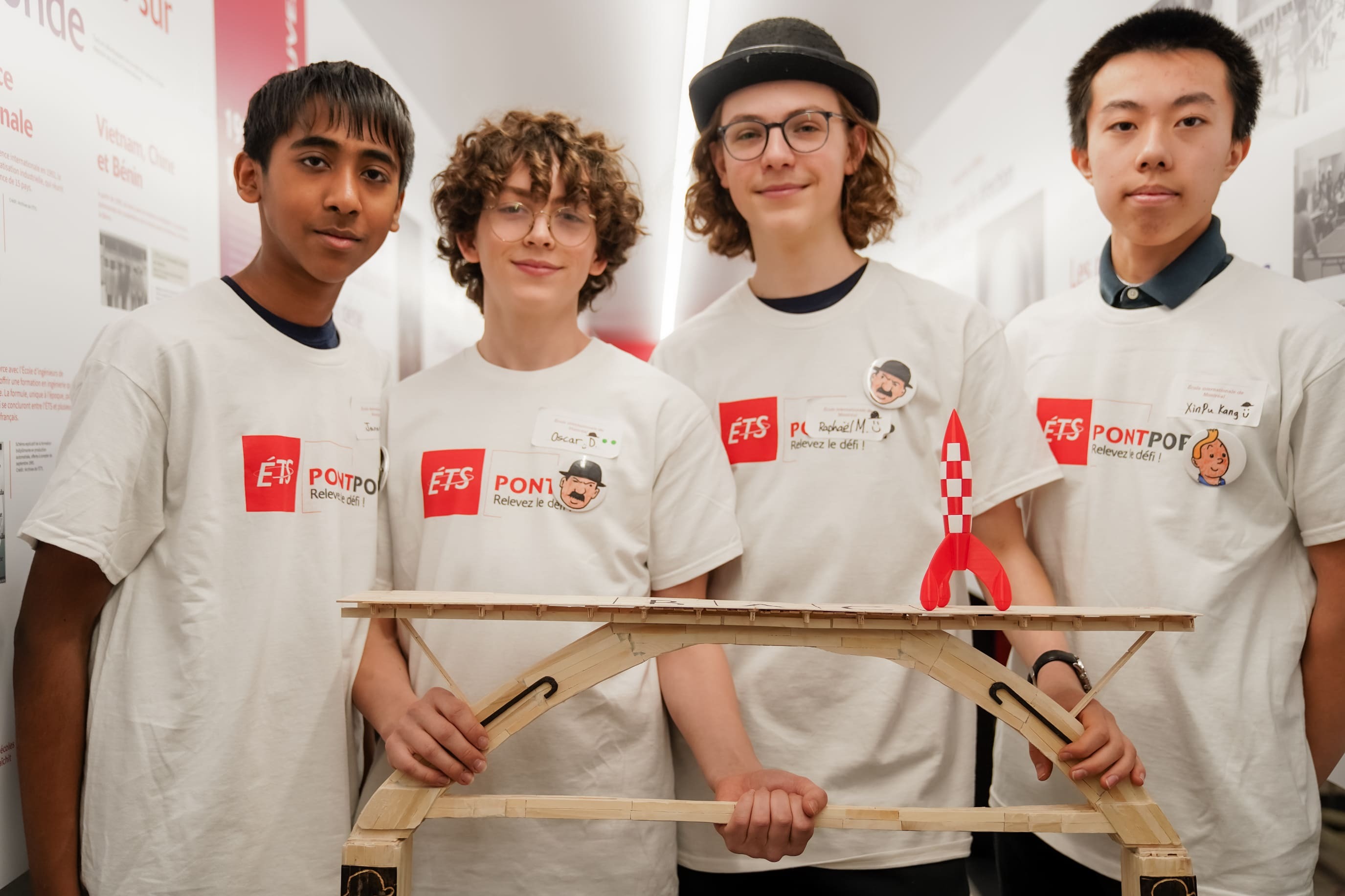 Quatre étudiants présentent leur projet de modèle réduit, démontrant leur créativité et leurs compétences techniques lors d'un concours.