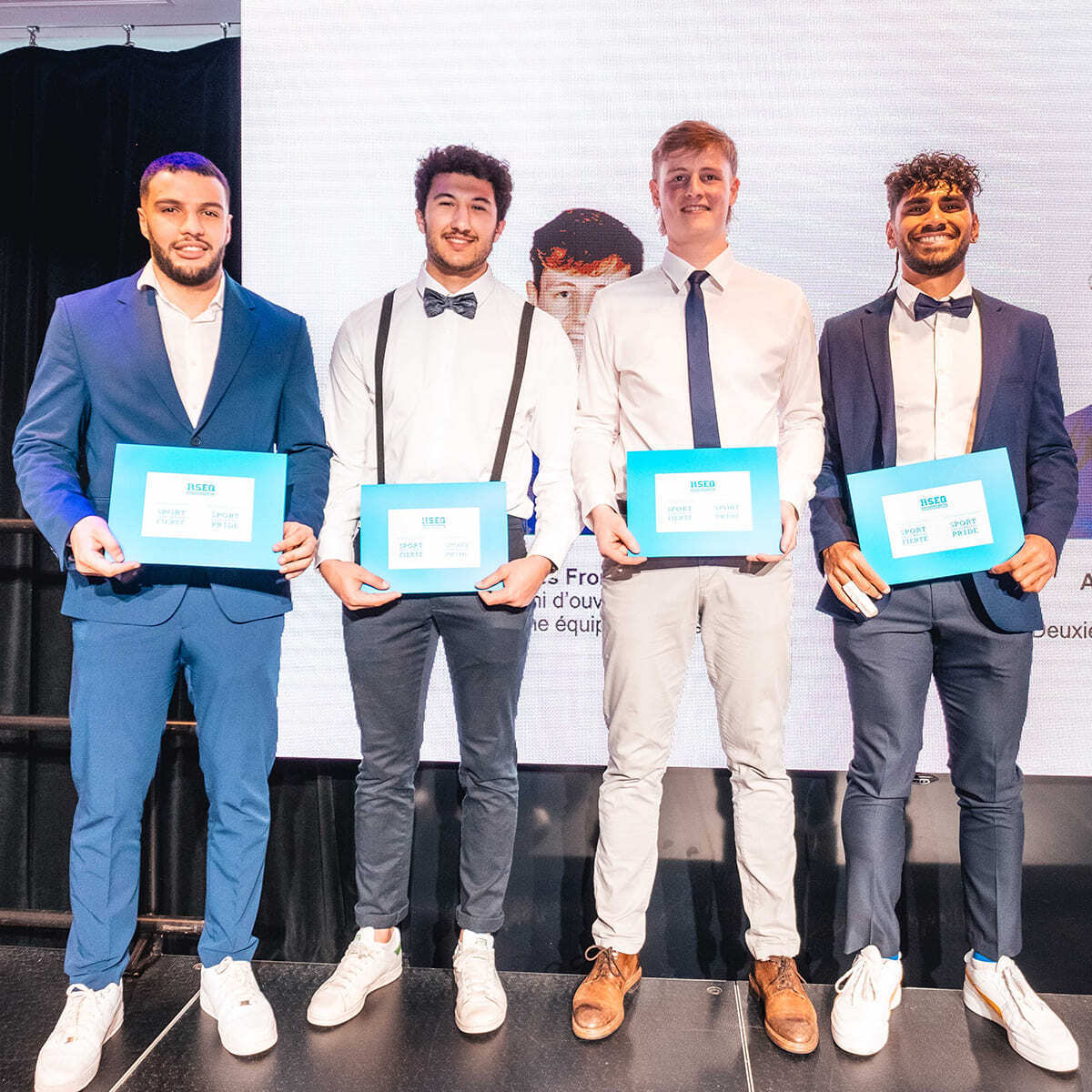 Quatre étudiants souriants tiennent des certificats de récompense.
