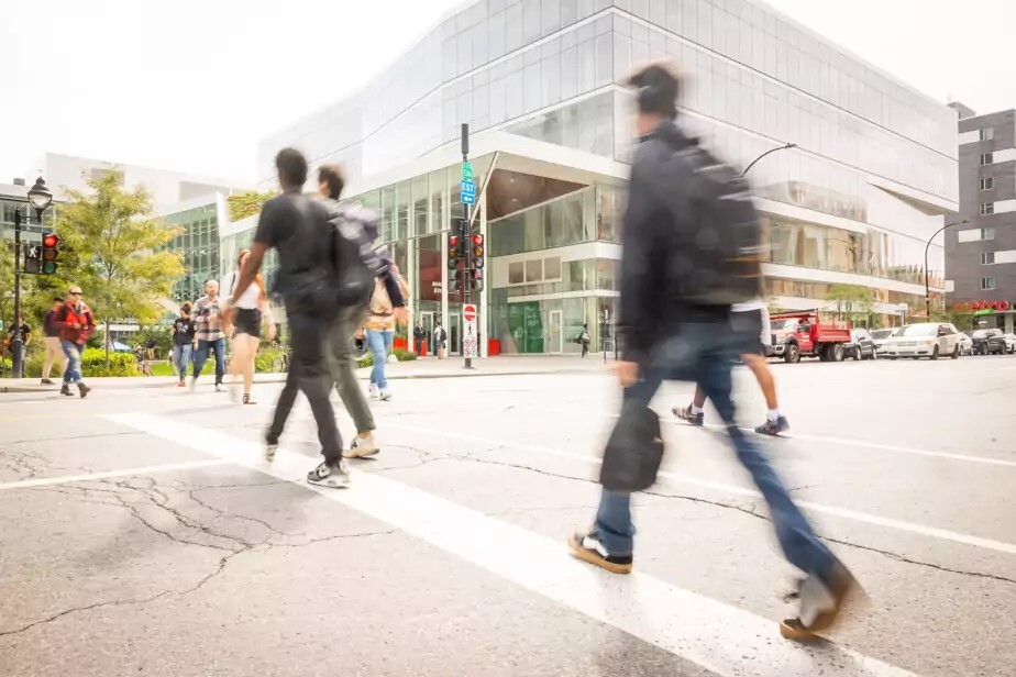 Étudiants traversant la rue devant un bâtiment moderne d'université technologique.