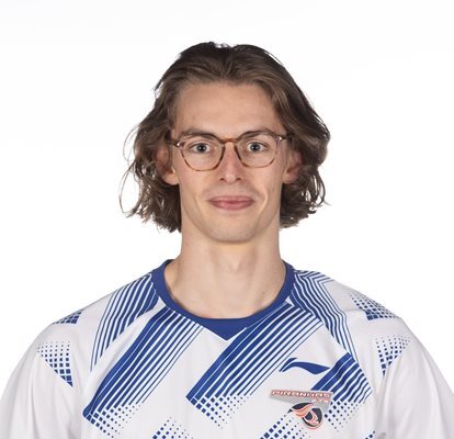 Homme souriant avec cheveux longs, portant des lunettes et maillot de sport rayé bleu et blanc.
