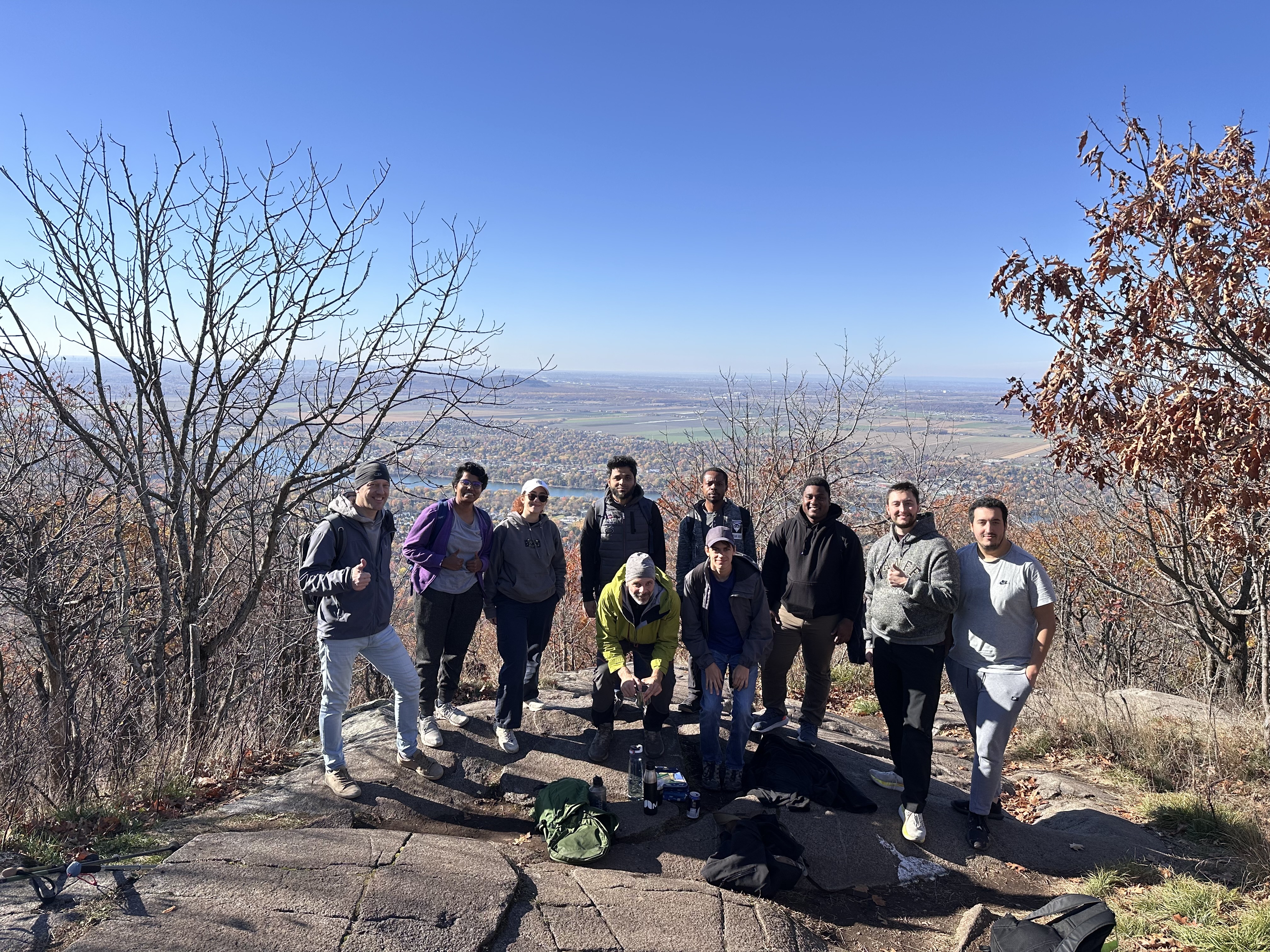 Groupe d’étudiants profitant d'une randonnée en montagne, avec une vue panoramique sur la vallée et un ciel dégagé.