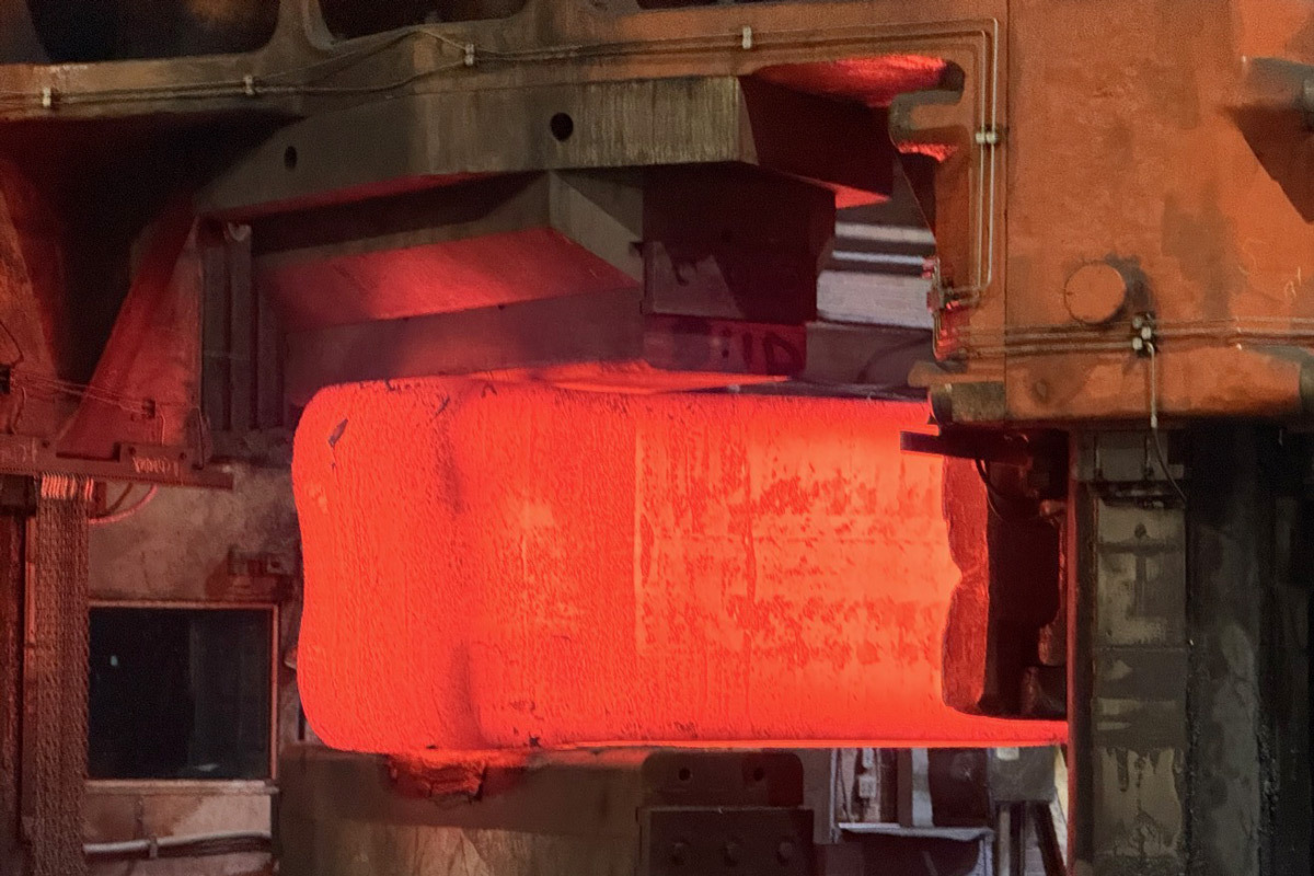 Un matériau incandescent est en cours de transformation dans un environnement industriel, illustrant le savoir-faire technologique avancé.