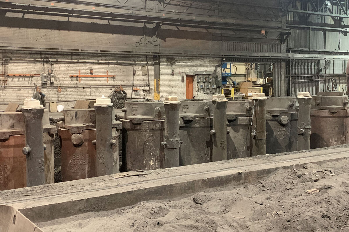 Atelier industriel avec de grands contenants, matériel varié et surface de travail en terre, symbole de la recherche en technologie avancée.