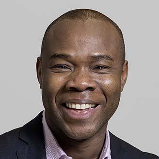 Homme souriant, costume, chemise à rayures. Exprime professionnalisme et joie.