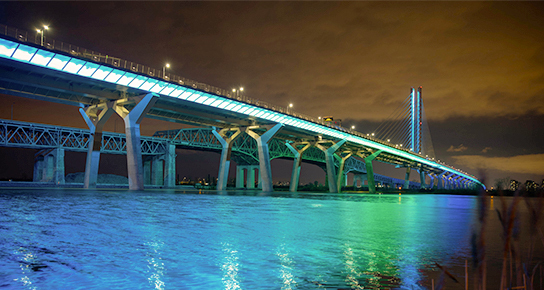 Pont illuminé en soirée, reflets sur l'eau, innovation et technologie.