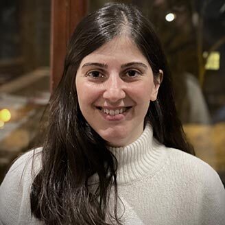 Smiling woman in a white sweater, exuding confidence and friendliness.