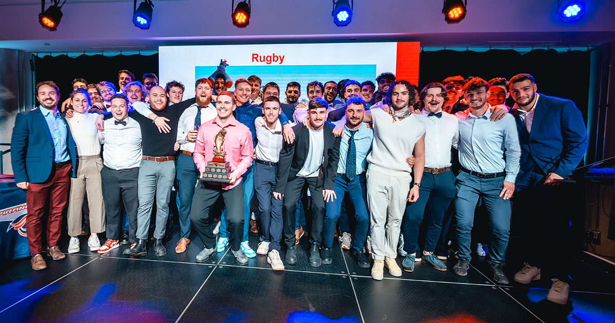 Équipe universitaire de rugby célébrant un succès avec un trophée.