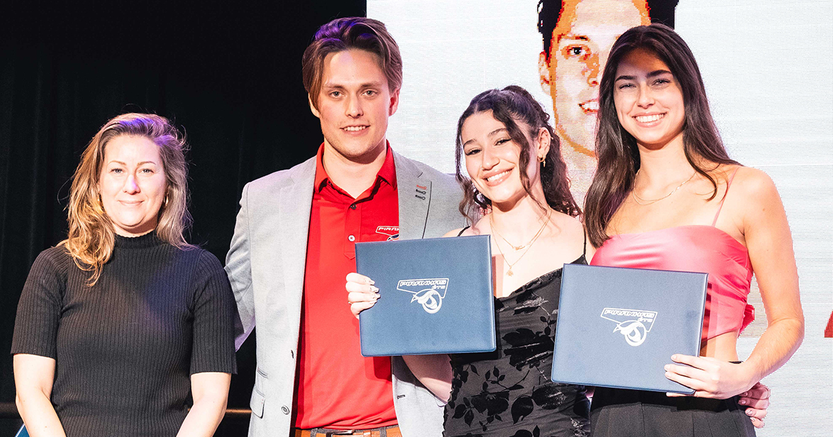 Remise de diplômes à des étudiants souriants en tenue de cérémonie.
