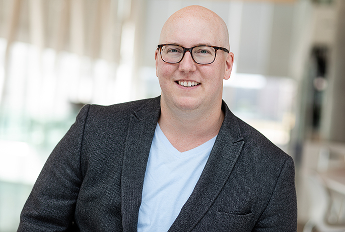 Homme souriant en veste, professionnel et confiant, représentant l'esprit universitaire innovant.