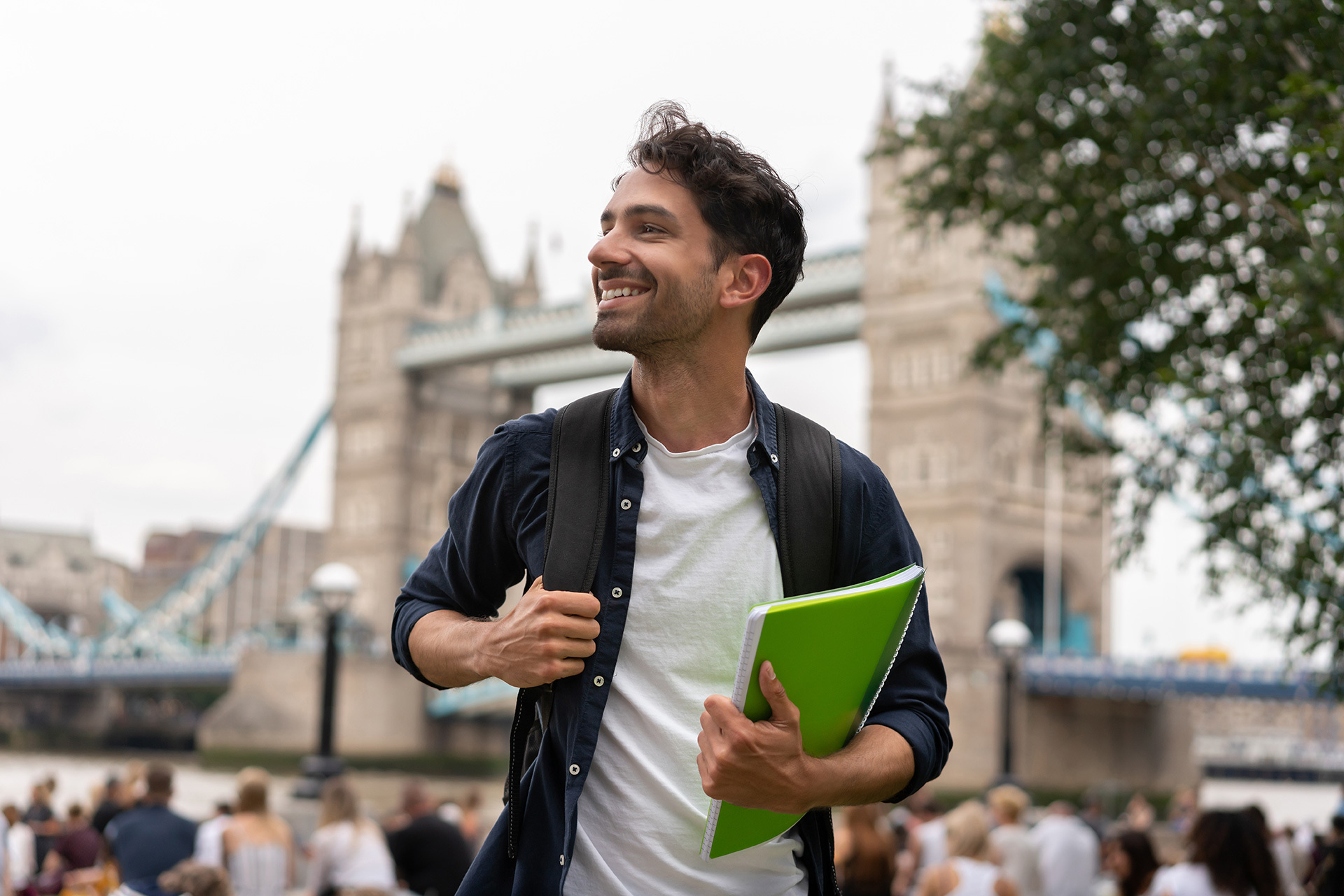 Étudiant souriant avec cahier devant le Pont de Londres.