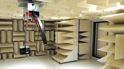 Chambre anéchoïque pour tests acoustiques avec mousse et bras robotique.