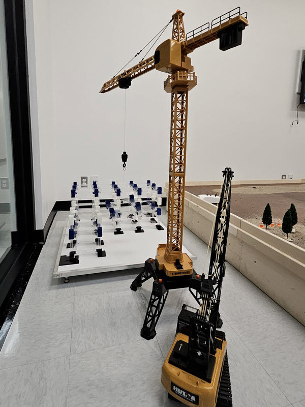 A model construction site featuring a tower crane and a machine, showcasing advanced engineering concepts in a learning environment.