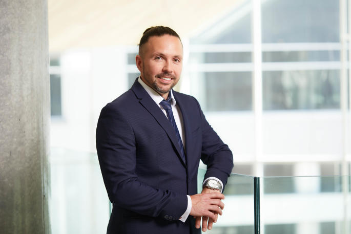 Professional in a suit stands confidently in a modern university building.