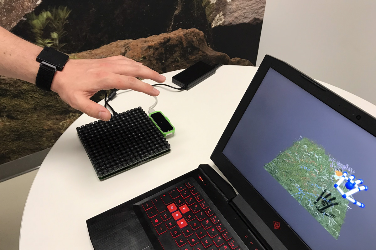 A hand interacts with a technological platform, displaying 3D data on a laptop. Innovations in action.