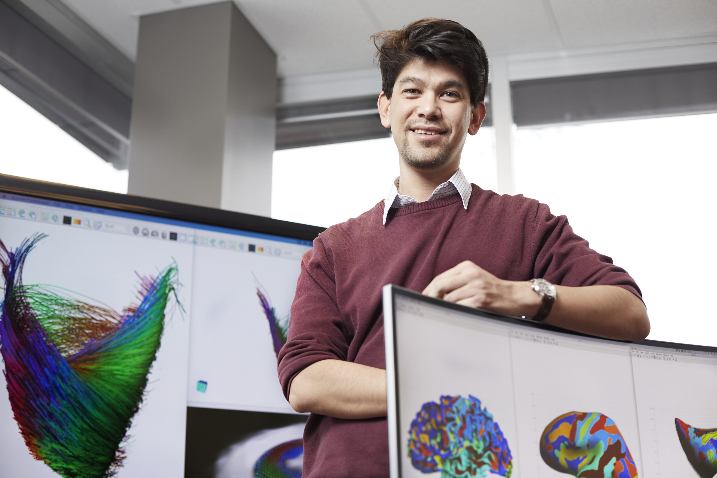 Étudiant en technologie devant des écrans avec des visualisations de données colorées.