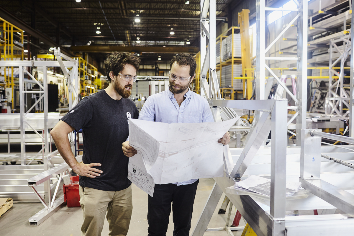 Deux ingénieurs examinent des plans dans un atelier industriel.