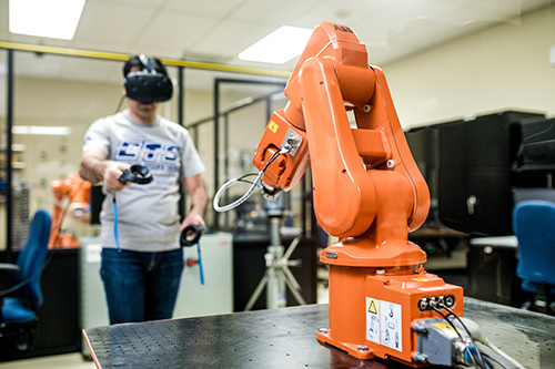 Étudiant avec VR interagit avec robotique dans un lab de technologie.