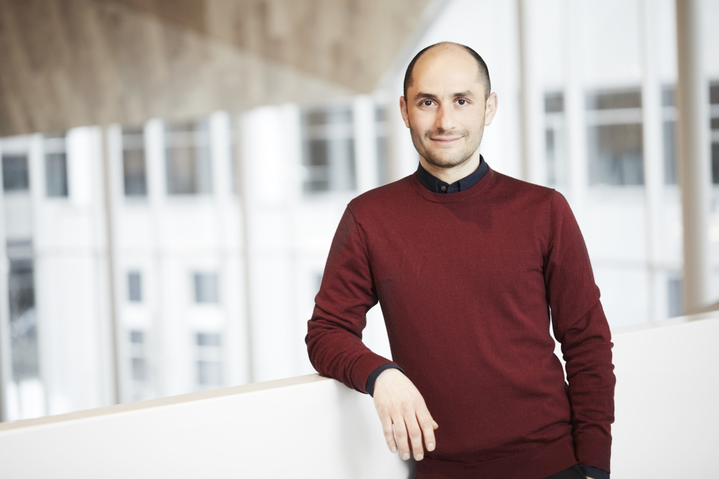 Professeur en technologie, souriant, vêtu d'un pull bordeaux, à l'intérieur de l'université.