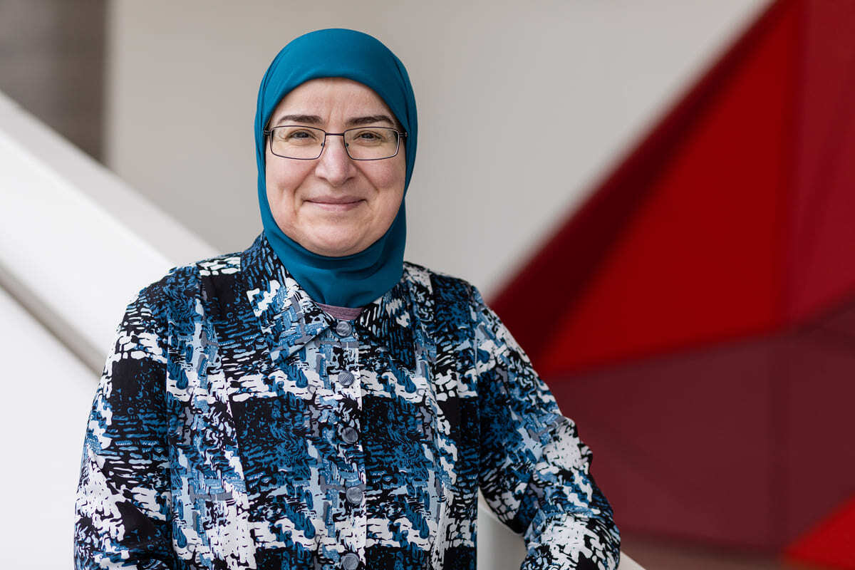Professeure en sciences, vêtue d'un hijab, souriante, symbolise diversité et savoir.