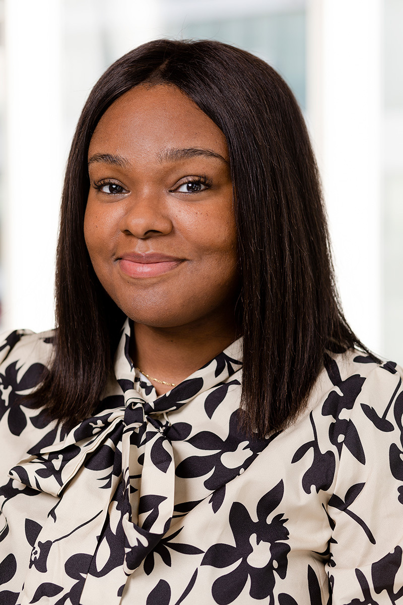 Confident professional in patterned attire against a bright office backdrop.