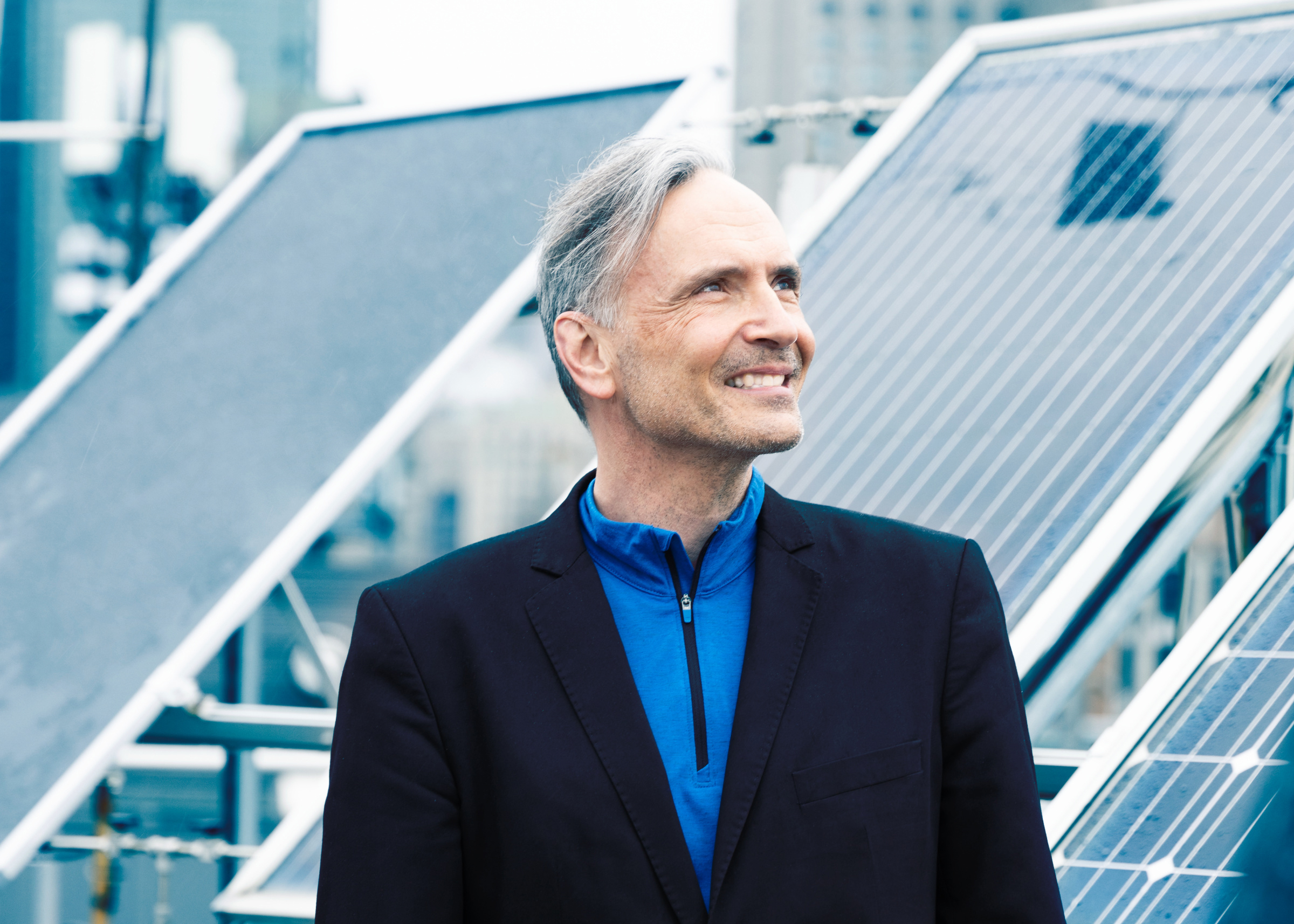 Professeur souriant devant des panneaux solaires, symbolisant l'innovation en énergie verte.