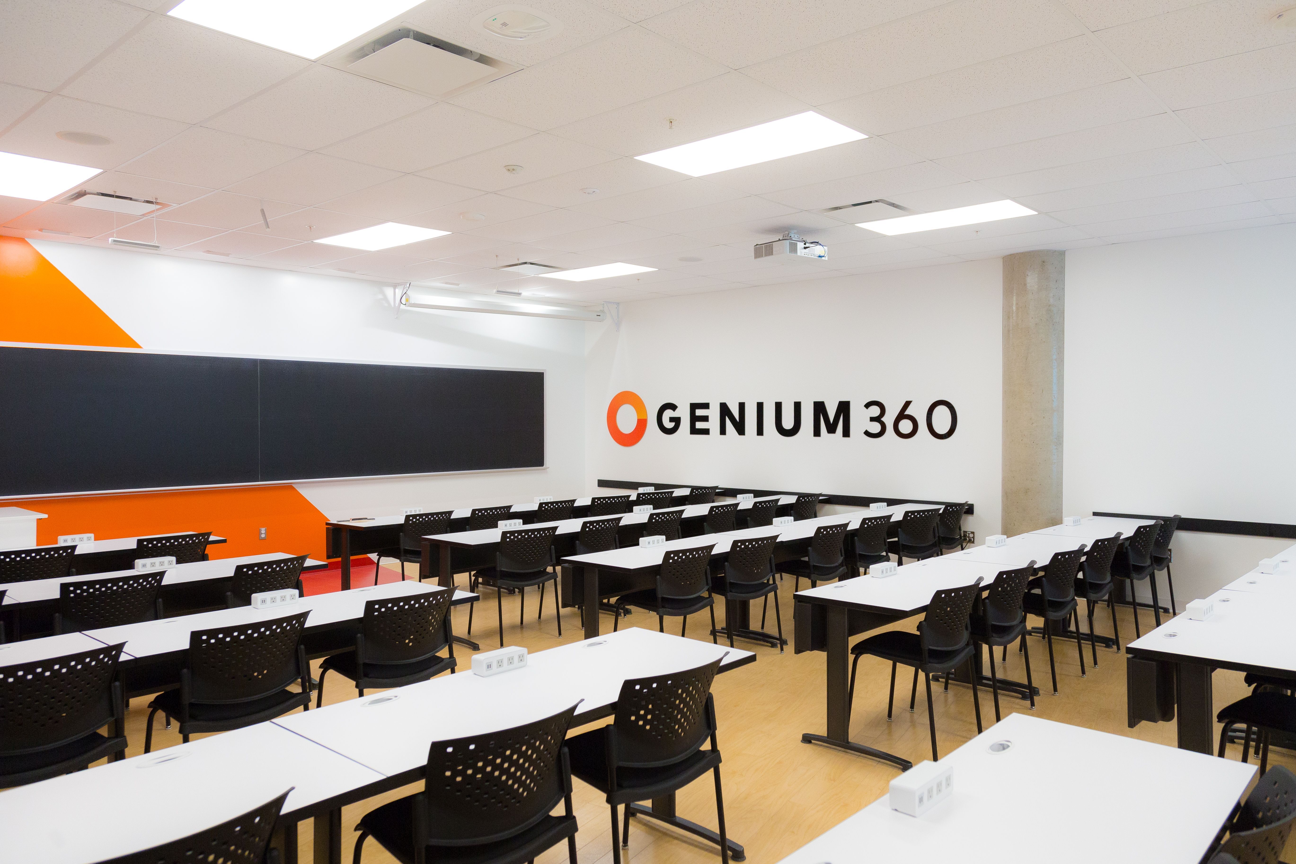 Salle de classe moderne avec mobilier noir et décoration orange.