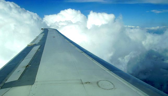 Vue aérienne à partir d'une aile d'avion, ciel dégagé avec nuages.