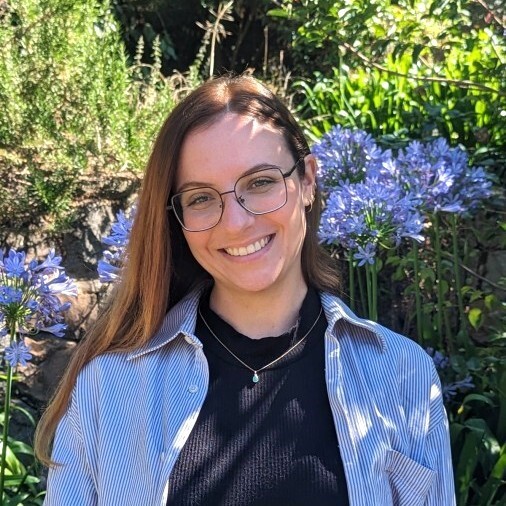 Étudiante rayonnante, elle sourit au milieu d'un jardin fleuri, mêlant nature et technologie avec élégance.
