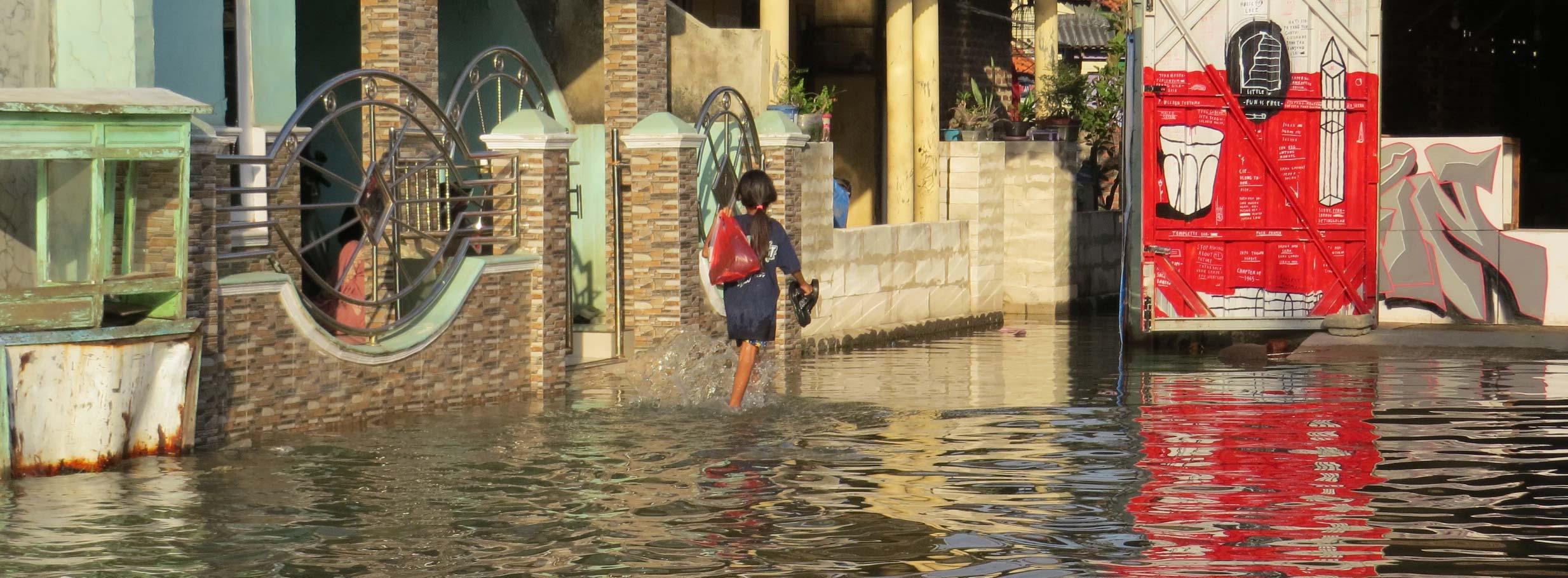 A person wades through floodwaters, showcasing resilience amidst urban challenges in a vibrant city setting.