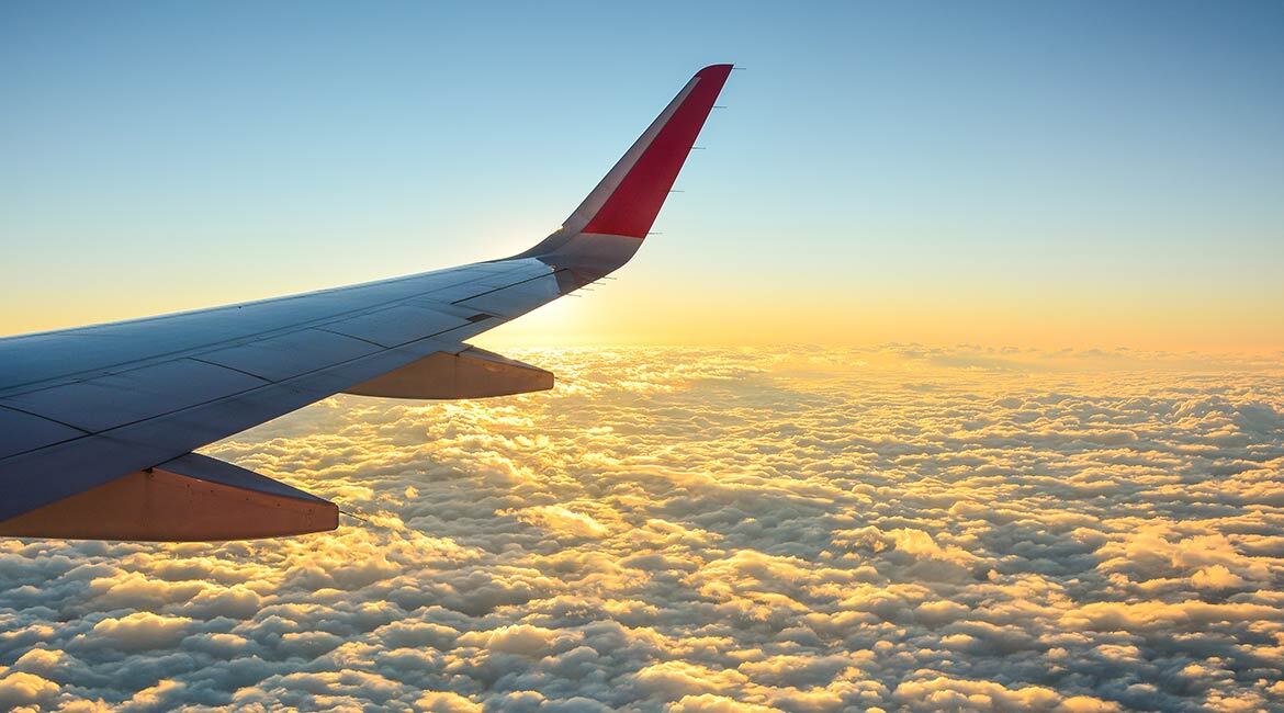 Vue aérienne de nuages au coucher du soleil, aile d'avion visible, inspirant voyage et technologie.