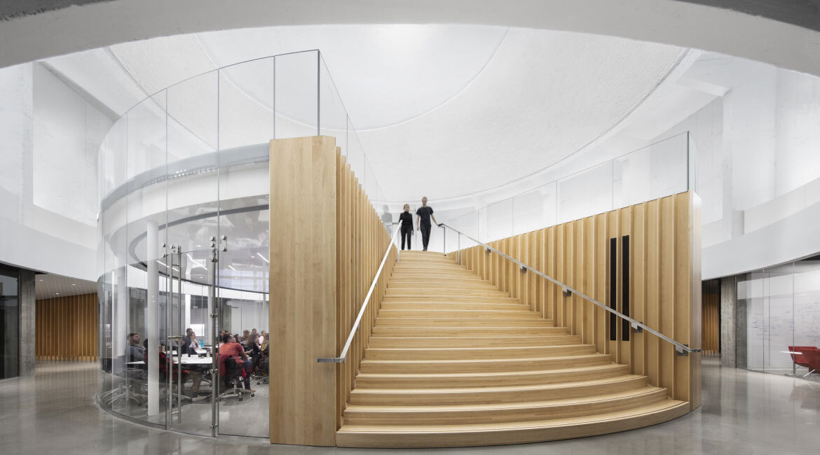 Escalier moderne en bois, design épuré et espace de réunion vitré dans une université technologique.