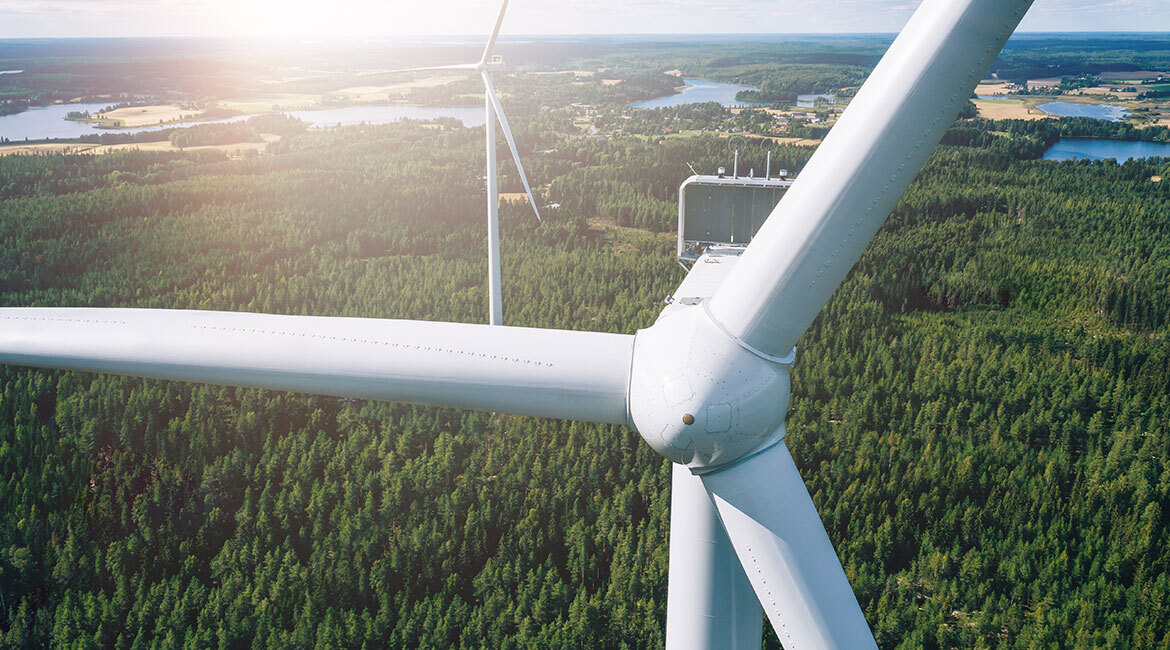 Vue aérienne d'éoliennes en forêt, symbole d'innovation en énergies renouvelables.