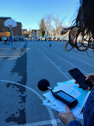Un terrain de jeu animé avec des enfants en activité, accompagné d'une personne utilisant des équipements de mesure et un téléphone.