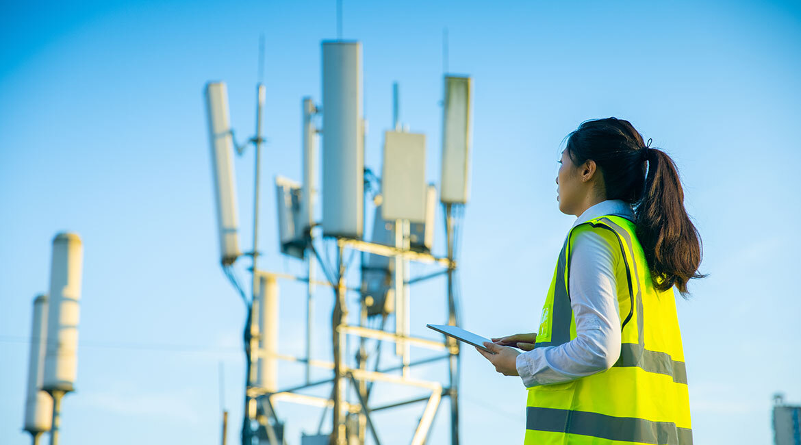 Ingénieure en télécommunications inspectant des antennes avec une tablette.