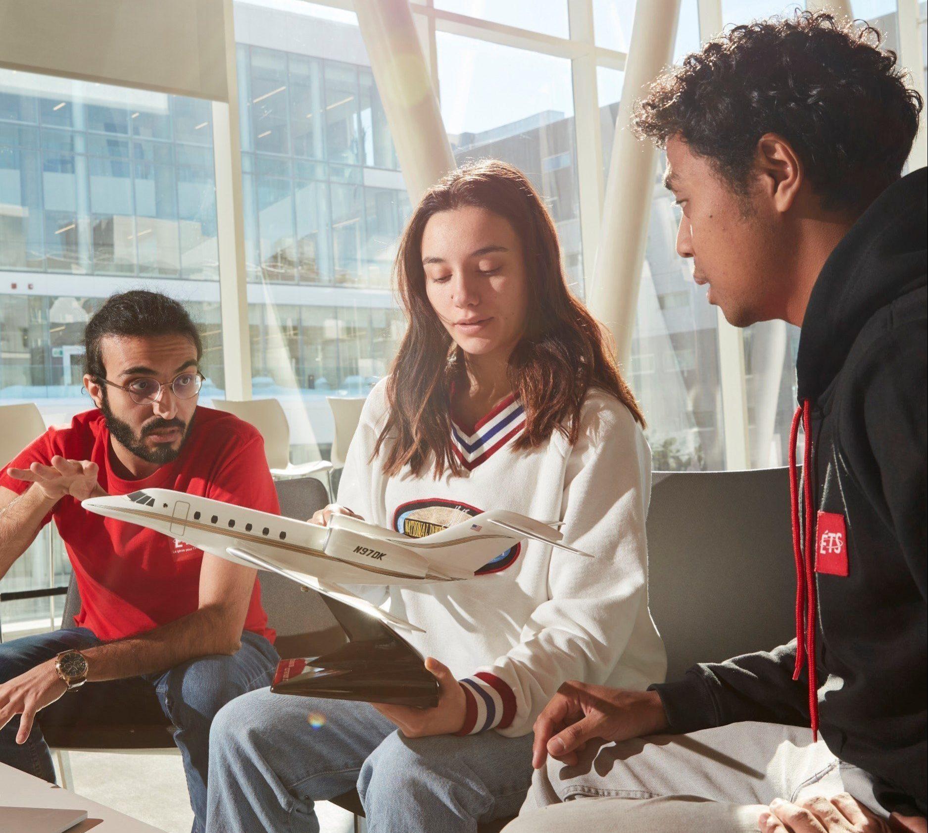 Des étudiants échangent des idées autour d'un modèle d'avion, illustrant la collaboration en ingénierie aérospatiale à l'université.
