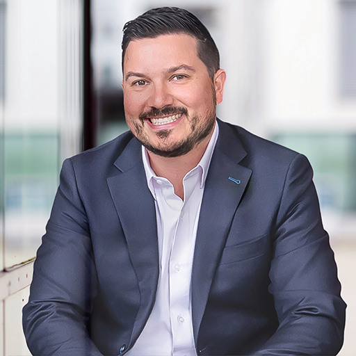 Professionnel souriant en tenue formelle, posant avec confiance dans un environnement moderne et lumineux. Ambiance accueillante et dynamique.