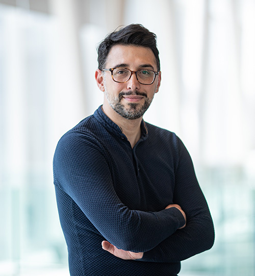 Confident tech university faculty member standing with arms crossed in a modern building.