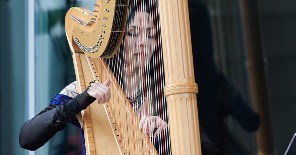 Une musicienne talentueuse joue de la harpe, captivant l'auditoire par sa grâce et sa maîtrise de l'instrument.