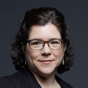Portrait professionnel d'une femme souriante avec des lunettes, mettant en valeur un style élégant et une expression amicale.