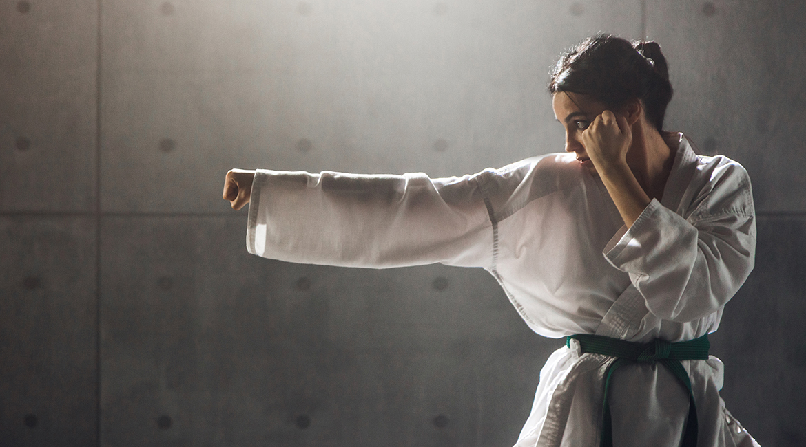 Étudiante en karaté pratique un coup de poing en gi blanc, ceinture verte.