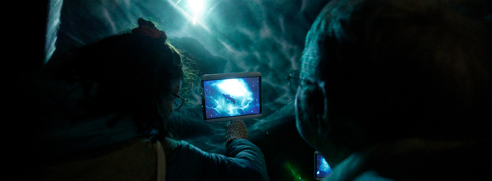 Des personnes explorent un univers virtuel à l'aide de dispositifs numériques, plongeant dans l'imaginaire et la technologie.