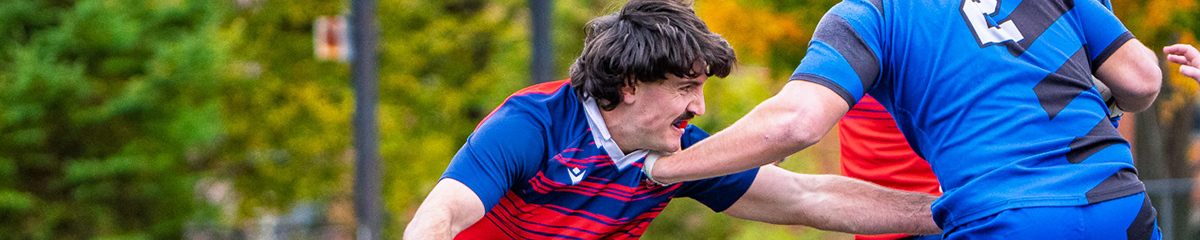 Des étudiants s'affrontent sur un terrain de rugby, illustrant l'esprit d'équipe et la compétition au sein de l'université.