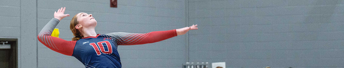 Une joueuse de volleyball s'apprête à servir, démontrant concentration et détermination sur le terrain.