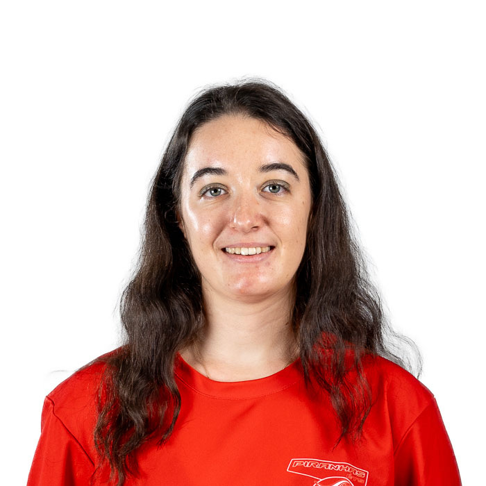 Étudiante en tenue sportive avec logo universitaire, souriante, fond neutre.
