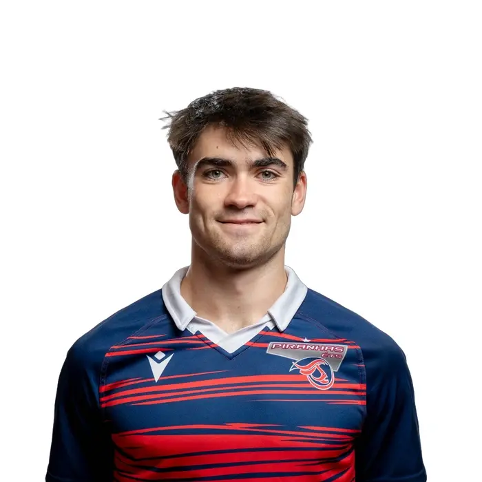 Étudiant dynamique en technologie, représentant des Piranhas, sourire confiant et déterminé dans un maillot aux couleurs vives.
