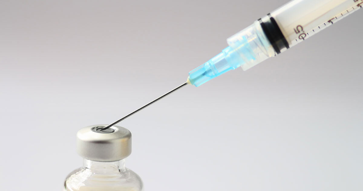 A syringe is drawn towards a vial, symbolizing medical preparation and advancement in healthcare technology.