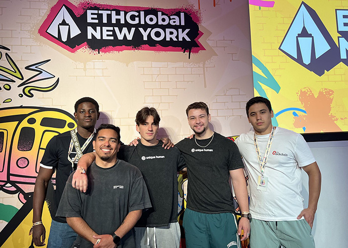Cinq participants au sommet ETHGlobal à New York, posant ensemble avec enthousiasme, reflétant l'innovation en technologie.